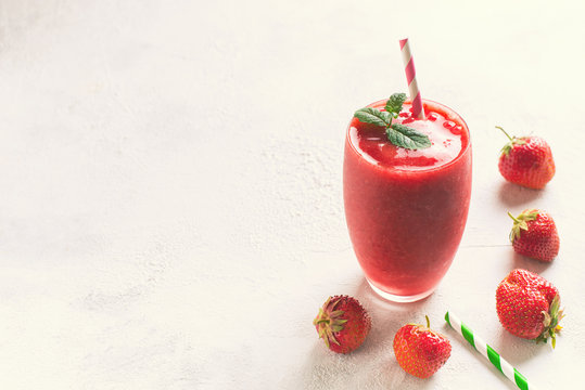 Strawberry smoothie and fresh raw berries on white background