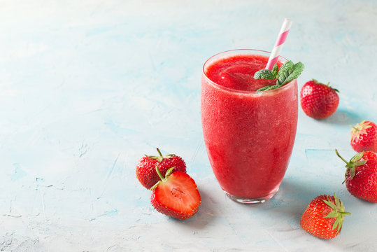 Strawberry smoothie and fresh raw berries on blue background