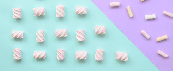 Colorful marshmallow laid out on violet and blue paper background. pastel creative textured...