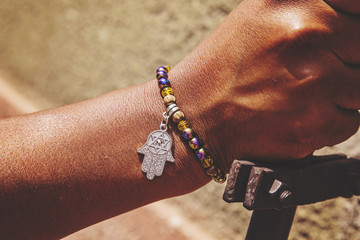 Male hand wrist with colorful bracelet and hamsa silver pendant