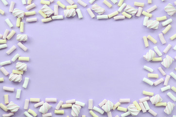 Colorful marshmallow laid out on violet paper background. pastel creative textured framework....