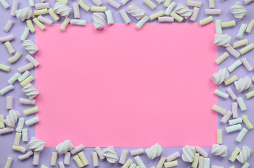 Colorful marshmallow laid out on violet and pink paper background. pastel creative textured...