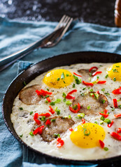 fried egg with ham sausage and pepper in a frying pan on table