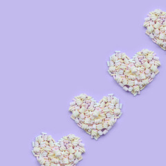 Colorful marshmallow laid out on violet and pink paper background. pastel creative textured hearts....