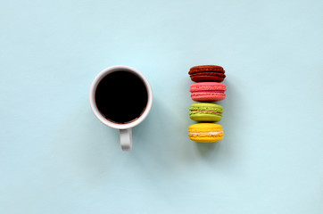 Colorful dessert cake macaron or macaroon and coffee cup on trendy pastel blue background top view. Flat lay composition