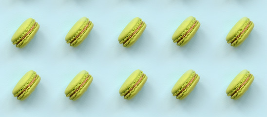 Green dessert cake macaron or macaroon on trendy pastel blue background top view. Flat lay pattern composition