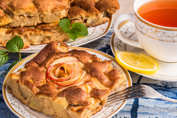 Apple pie cake on plate with cap of tea. Famous tart with different types of recipes. It is one of a number of American cultural icons. 