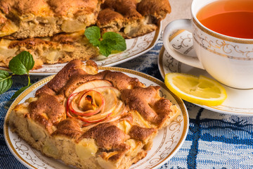 Apple pie cake on plate with cap of tea. Famous tart with different types of recipes. It is one of a number of American cultural icons. 