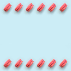 Pink dessert cake macaron or macaroon on trendy pastel blue background top view. Flat lay pattern composition