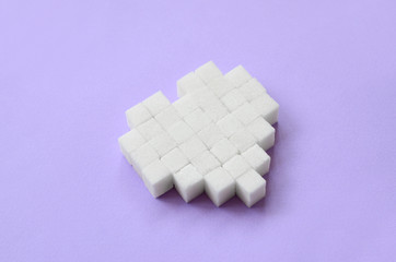 A heart made of sugar cubes lies on a trendy pastel violet background