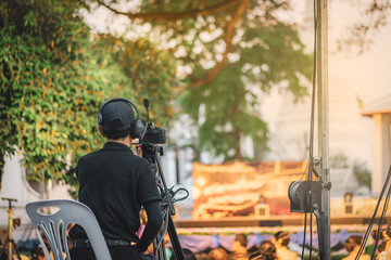 Back of cameraman using a professional camcorder outdoor filming music show or mini concert at...