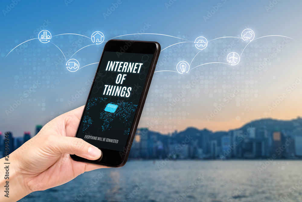 Poster hand holding mobile with internet of things (iot) word on screen with icon feature glowing in air wi