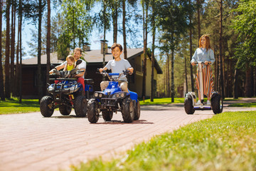 We love driving. Joyful cute kids spending time with their parents and driving ATVs