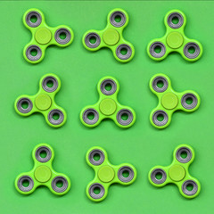 Many green fidget spinners lies on texture background of fashion pastel green color paper in minimal concept