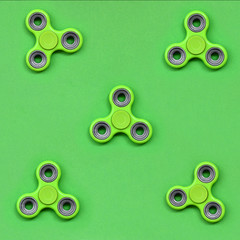 Many green fidget spinners lies on texture background of fashion pastel green color paper in minimal concept