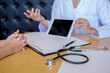 Patient listening intently to a male doctor explaining patient symptoms or asking a question as they discuss paperwork together in a consultation
