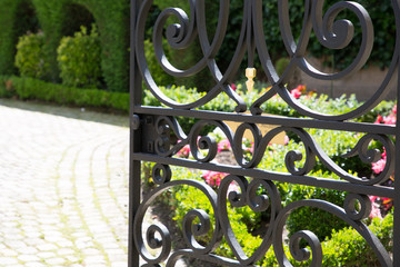 a wrought iron gate open to the garden and its slab driveway