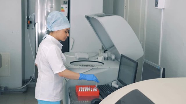 A nurse performs blood tests, using modern automated medical equipment.