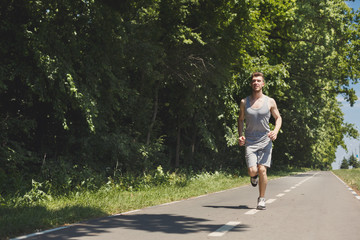 Fototapeta premium Young man jogging on treadmill in park, copy space