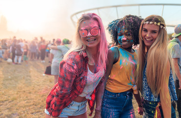 Multiethnic group of friends with colorful powder on clothes and bodies at summer holi festival having fun together, copy space