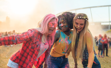 Multiethnic group of friends with colorful powder on clothes and bodies at summer holi festival...