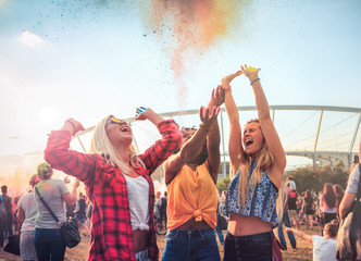 Multiethnic group of friends throwing colorful powder at holi festival