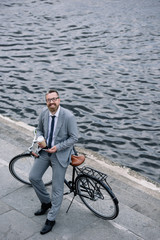 businessman with coffee to go and smartphone standing with bicycle on quay