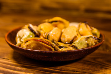 Ceramic plate with prepared mussels on wooden table