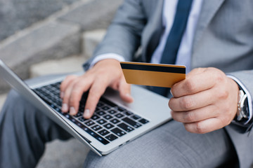 cropped view of man shopping online with laptop and credit card