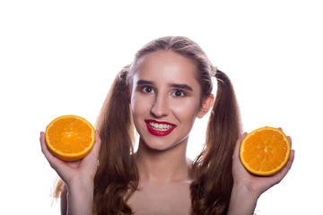 Smiling brunette shirtless girl holding pieces of orange in her hands, standing on a white background