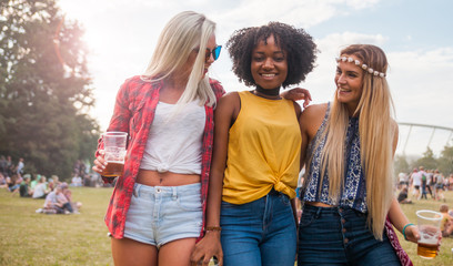 Group of friends with beer in hands at summer music festival outdoor