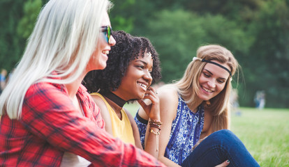 Group of friends having fun together sitting on grass