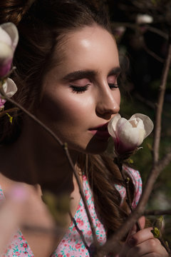 Closeup shot of glamor brunette woman standing near blooming magnolia flowers