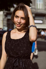 Gorgeous brunette model with bronze tan posing on the street in a fashionable dress
