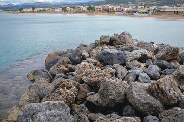 Rocks of a breakwater on Mediterranean Sea beach in Kissamos town on the Crete Island, Greece