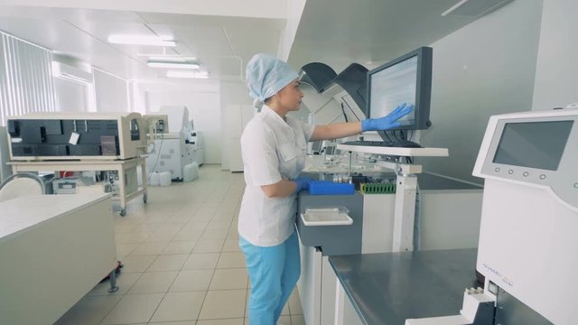 A woman works in a laboratory room with equipment.