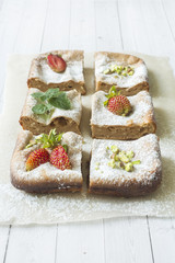 Cottage cheese casserole portion with strawberries and mint, pistachio nuts on a light background. concept of Breakfast