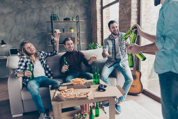 Cropped view of visitor bringing bottles with beer to his stylish, successful, attractive friends with modern hairstyle who extremely happy, glad to see him, having snacks, chips on the table