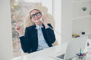 Portrait of executive corporate woman in eyewear speaking by phone using handset enjoying...