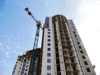 Fototapeta na wymiar Building and crane under construction against blue sky.