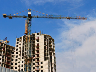 Fototapeta na wymiar Building and crane under construction against blue sky.