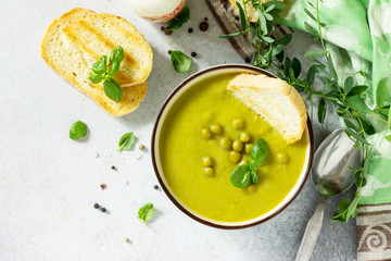 Puree soup green peas with croutons in a bowl on a light slate background. The concept of healthy eating.  Diet menu. Top view with copy space.