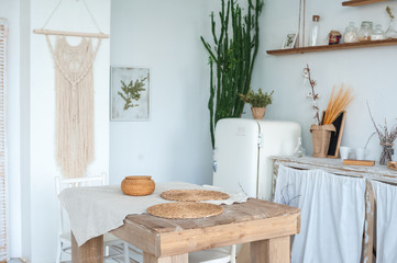 White textured kitchen in the style of shabby. A large textured table in the ecological style and Loft style. Rustic wicker napkins, light green tablecloth, diy.