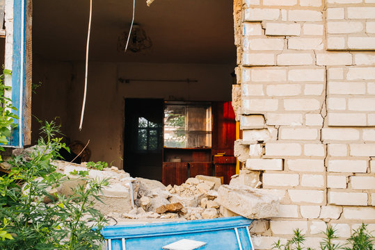 Ruined Wall Of The House. Hit A Military Projectile After A Car Accident. Destruction And Earthquake. Migration And Crisis. The Brick House Is Destroyed. The Window And The Wall Are Broken.