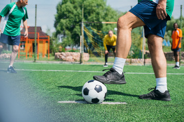 partial view of multicultural elderly friends playing football together