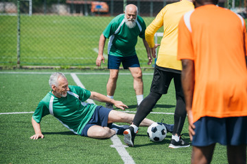 partial view of multicultural elderly friends playing football together