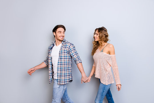 Follow me! Portrait of sexy positive couple holding hands going to happy dreamy future together isolated on grey background
