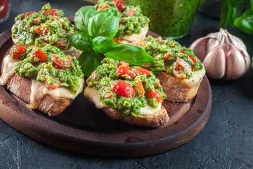 Bruschetta with fresh pesto, mozzarella and cherry tomatoes on cutting board