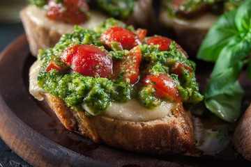 Bruschetta with fresh pesto, mozzarella and cherry tomatoes on cutting board