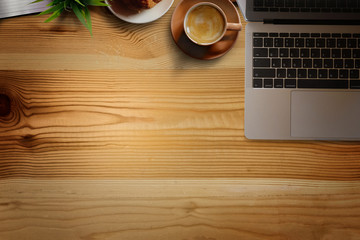 Office wooden desk with laptop, coffee cup and plant. Business workspace and copy space.